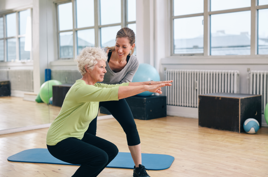 Elderly woman doing exercise with her personal trainer