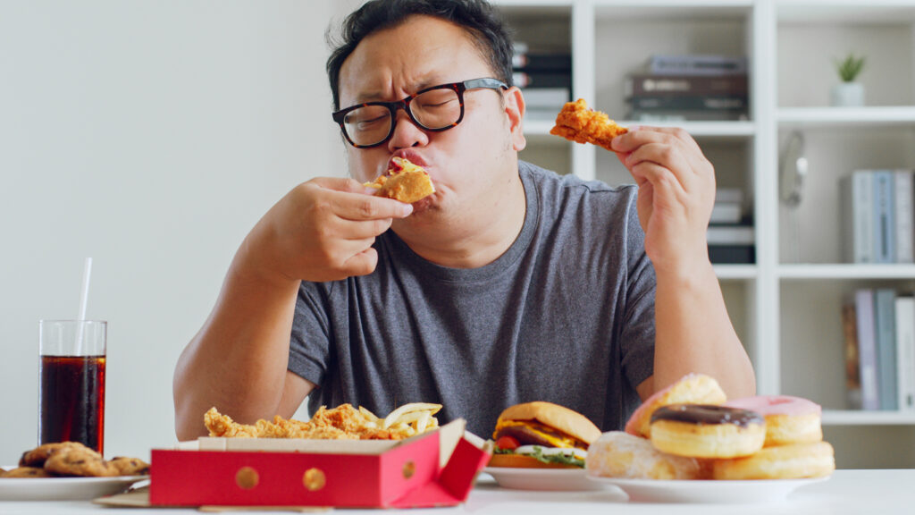 Asian man enjoying unhealthy junk food, hamburger, pizza, fried chicken, heartburn, overweight, acid reflux, GERD